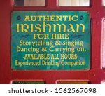 Small photo of Banos, Ecuador - March 16 2019: 'Authentic Irishman for Hire' funny poster on the red door of Abby's Hideaway in the touristic town of Banos, Ecuador