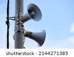 Small photo of Loudspeakers on pole, alarm siren in city. Two public address system speakers on blue sky background