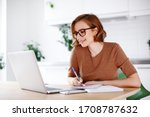 Woman on remote work or online education, using laptop computer, making  notes, indoors at office or home at daytime. Online business, young professional at workplace. Working from home.