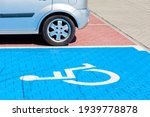 Blue car parking spot for the disabled, handicapped. Wheelchair symbol painted on the ground, parking lot vehicle space, closeup, angled view, nobody. Disability and city transportation concept