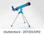 Blue toy telescope on a tripod, single object isolated on white background. Stargazing, space observation science instruments, tools for young kids, children, astronomy hobby conceptual symbol, nobody