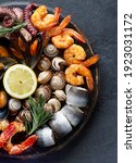 Small photo of Seafood charcuterie platter board with shrimp, oysters, fish and octopus on black background. Top view, close up