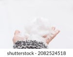 Snow hand close-up. A woman's hand in a gray sweater holds a lump of snow in the bright sunlight. The concept of cold winter snowfall, weather changes. Fabulous mood, snowball fight time on the street