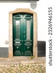 Small photo of Old wooden door with wrought iron door knockers on white facade in Tavira, Portugal