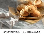 Kaiser or Vienna rolls in bread basket with towel. Table covered with beige linen tablecloth. Sun light with long shadows.