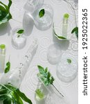 Small photo of Cosmetic skincare background. Herbal medicine with green leaves. Natural sunlight, long shadows. Splashes of water, splashes. Chemical glassware, petri dishes, vials. Natural skincare background.