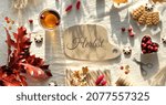 Small photo of Text Herbst means Autumn in German language. Autumn decorations - cranberry, cookies. tea and dry oak leaves. Flat lay, top view on uncolored textile. Fall background, sunlight with long shadows.