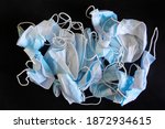 Small photo of A lot of used crumpled protective medical masks on a dark black background. Problems of self-preservation, isolation, infection and recovery. Background and backdrop