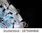 Small photo of Used protective medical masks on a dark black background. Problems of self-preservation, isolation and environmental pollution. Close-up. Free space for an inscription