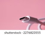 USB Type-C connector with a white wire on a pink background. Selective focus. Macro. Close-up