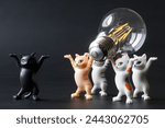 Small photo of Funny toy kittens carry a modern energy-saving LED lamp in their paws. An educational concept for saving electricity. Electrification. Toy world. Photo. Close-up