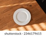 Small photo of Ceramic white flat plate for food on wooden table top view
