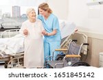 Small photo of Nursing lady helps frail elderly woman to wheelchair at the hospital
