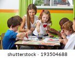 Many children painting together with nursery teacher in a kindergarten