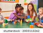 Children play together with building blocks in the international kindergarten with a kindergarten teacher