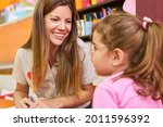 Small photo of Friendly childminder or kindergarten teacher talks to a girl in daycare