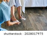 Small photo of Geriatric nurse helps frail senior citizen in a wheelchair to put on shoes in the nursing home