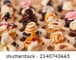 Small photo of Many different small colorful cupcakes with decorations in a pastry shop