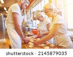 Small photo of Bakers bake small rolls together in bakery as a family manufactory