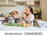 Smiling woman enjoying with son and daughter while preparing soup in kitchen at home