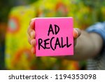 Small photo of Hand holding an pink Paper with word AD RECALL, Business Concept. colourful background