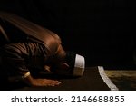 Small photo of A picture of men perform "sujud" on praying mat during at night. Sign of devout and repent to Allah.