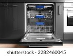 Modern built-in stainless steel dishwasher with open door in the kitchen front view. Household kitchen appliances. Dishwashing equipment.