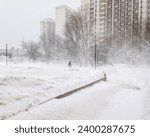 A lonely silhouette of a man walking through a snowstorm along a city street on a winter day. Snowfall, blizzard and wind in December in Moscow.