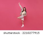 Happy Asian woman smiling and jumping while celebrating success isolated over pink background.