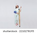 Small photo of Asian teenage woman wearing a patient gown put on a cast Use a crutch to walk and Bandaged head due to accidental injury standing pointing to empty space with awesome smile insurance concept.