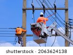 Small photo of 2 electricians with articulated boom lift and Disconnect Stick tool are Working to install electrical transmission on Power Pole against blue sky background