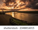Small photo of Petitcodiac River with dramatic sunrise cloudscape at Bore Park or Parc Bore Riverfront Walk, a popular place to watch the tidal bore in Moncton, New Brunswick, Canada