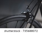 Detail of the rear brake and frame of a road bicycle on a silky black background.
