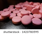 Small photo of Pink Nitroglycerin pills scattered on glossy black background - 003