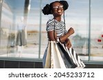 Happy beautiful young African American woman wearing black glasses, with black shopping bags, Black Friday, sale, fashion, people