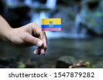 Small photo of Poor Ecuador in the hands of powerful people. Young man holds flag of Ecuador near stream. Concept of humanity and dominance. Prove of depraved and avariciousness. Colour man waves with flag.