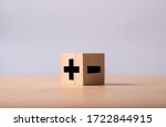 Black of plus and minus sign in opposite side of wooden cube.