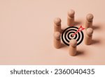 Small photo of wooden miniature figure team encompass to dartboard with arrow for setup business objective target and goal concept.