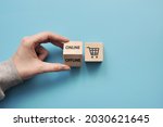 Wooden cubes with a picture of shopping baskets and the inscription: online and offline. Symbol for online or offline purchases