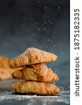 Small photo of Close up of pile of delicious croissants on a dark background. Homemade croissants. Sugar glass falling. Vertical.