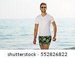 Smiling dude on beach wearing t-shirt and shorts, portrait