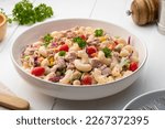 Homemade macaroni salad with elbow pasta and canned tuna, carrot, Purple cabbage, corn, tomato, green peas and mayonnaise dressing in a white plate on wooden table.