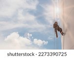 Small photo of Closeup male worker inspected tank whites wearing safety first harness rope safety line working at a high tank shell plate sunlight.