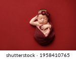 Newborn girl on a red background. Photoshoot for the newborn. A portrait of a beautiful newborn baby girl	