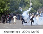Small photo of Supporters of Pakistan's former Prime Minister Imran Khan remove tear gas shell fired by police to disperse them during a protest against the arrest of their leader, in Lahore, Pakistan, May 10, 2023.