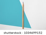 Small photo of Minimalist template with copy space by top view close up photo of wooden pencil isolated on white paper and combination with blue green quirk shape graphic. Flash light made smooth shadow from pencil.