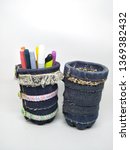 Small photo of Handmade craft recycle bottle and jeans become pencil stationary case desk. Tube box shape with top hole. Decoration with sand, button and bordir embroidery. Work process cut sewn taped glued dry.