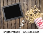 Table with popcorn bottle and Netflix logo on Apple Ipad mini and earphone. Netflix is a global provider of streaming movies and TV series.