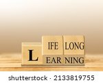 Small photo of Lifelong learning symbol. Turned wooden cubes for concept words. Business, educational and lifelong learning concept.