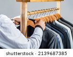 Small photo of Man suit, tailor in his workshop. Fashion man in classical costume suit. Tailor, tailoring. Stylish men's suit. Male suits hanging in a row. Men clothing, boutiques.